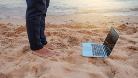 legs of a young man in suit with laptop working on the seaside