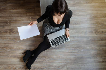 top view of a hot brunete in office outfit sitting on the floor and working on computerの写真素材