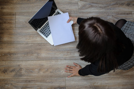 top view of a hot brunete in office outfit sitting on the floor and working on computer
