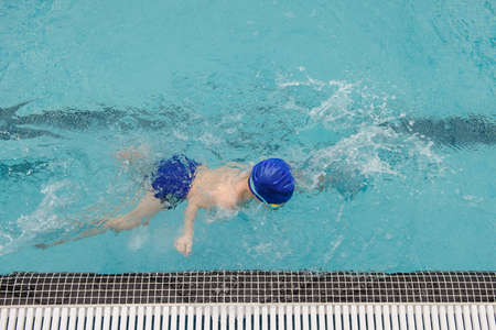 top view of a 7-year boy playing and swimming in the swimming poolの写真素材