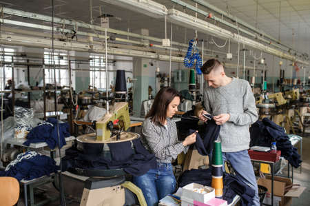 close up photo of a young man and a woman analyzing the work at the linking machine for knitting in textile industryの写真素材