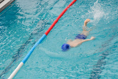 top view of a 7-year boy playing and swimming in the swimming poolの写真素材