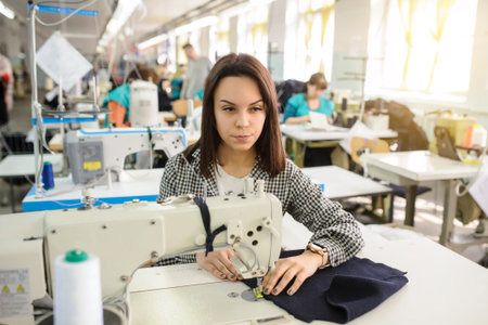close up photo of a young woman sewing with sewing machine in a factory