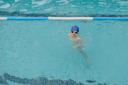 top view of a 7-year boy playing and swimming in the swimming poolの写真素材