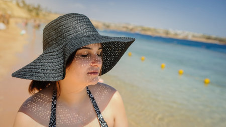 close up photo of a young woman in swimsuit and a blue big sunbathing on the beach