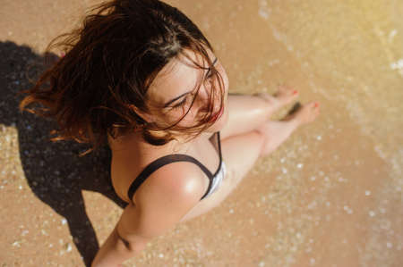 top view of a sexy young woman sitting on the sand on the beachの写真素材