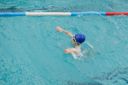 top view of a 7-year boy playing and swimming in the swimming poolの写真素材