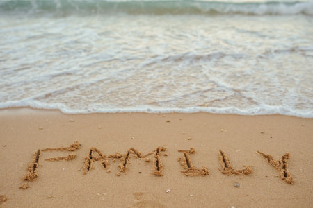 top view FAMILY lettering on the sand of a beach with wave and sunshineの写真素材