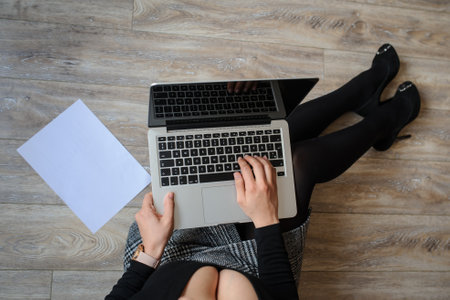top view of a hot brunete in office outfit sitting on the floor and working on computerの写真素材