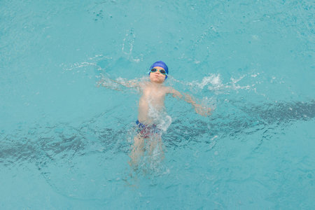 top view of a 7-year boy swimming backstroke in a swimming poolの写真素材