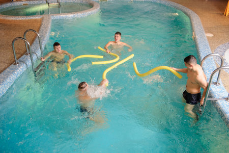 close up photo of 4 men relaxing in swimming pool in a spa centreの写真素材