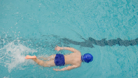 top view of a 7-year boy playing and swimming in the swimming poolの写真素材
