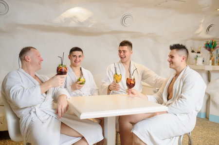 close up photo of 4 men in white gowns sitting around a table and drinking sangria and limonadeの写真素材