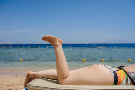 View of a sexy young woman laying on the lounger on the beachの写真素材