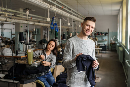 close up photo of a young man analyzing a piece of work and a woman working with linking machine for knitting in textile industryの写真素材