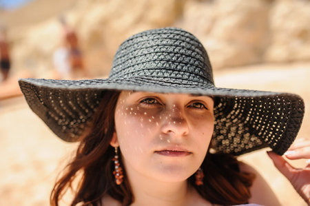 close up photo of a young woman in swimsuit and a blue big sunbathing on the beachの写真素材