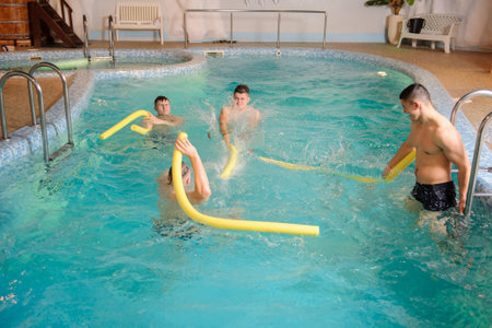 close up photo of 4 men relaxing in swimming pool in a spa centreの写真素材