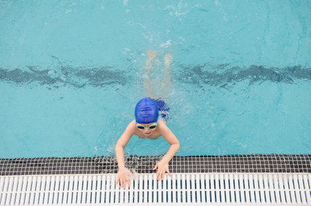 top view of a 7-year boy playing and swimming in the swimming poolの写真素材