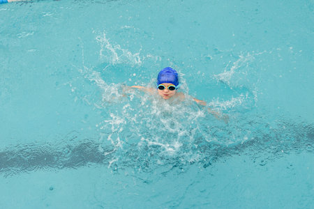 top view of a 7-year boy playing and swimming in the swimming poolの写真素材