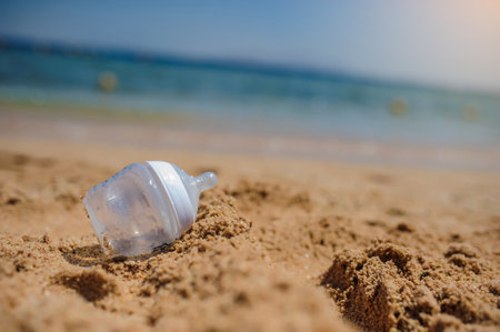 close up photo of a bottle for milk on the sand on the beachの写真素材