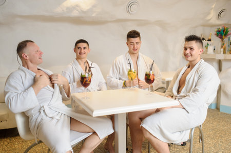 close up photo of 4 men in white gowns sitting around a table and drinking sangria and limonadeの写真素材