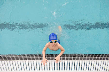 top view of a 7-year boy playing and swimming in the swimming poolの写真素材