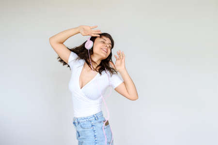 close up photo of a happy brunette with pink headphones in white blouse and denim skirtの写真素材