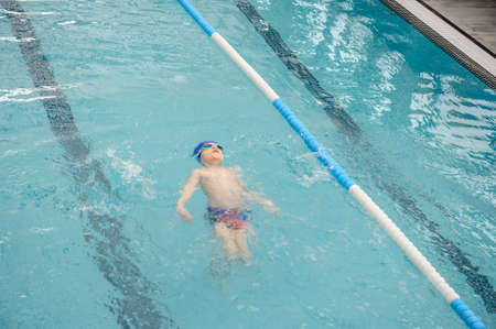 top view of a 7-year boy swimming backstroke in a swimming poolの写真素材
