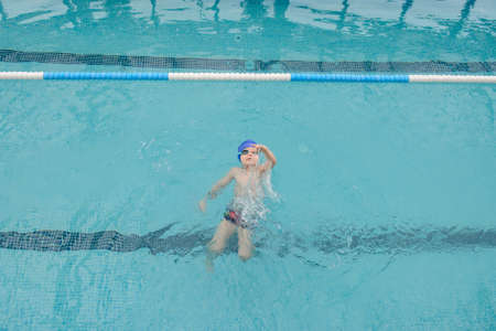 top view of a 7-year boy swimming backstroke in a swimming poolの写真素材