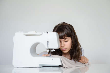 close up photo of a sexy brunette working at the sewing machineの写真素材