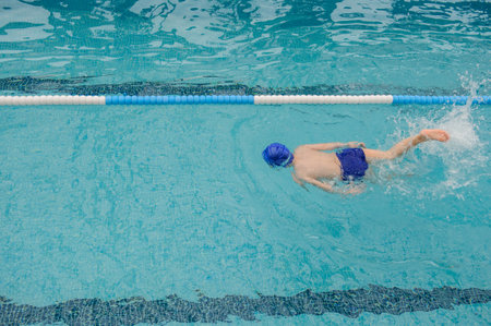 top view of a 7-year boy playing and swimming in the swimming poolの写真素材