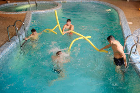 close up photo of 4 men relaxing in swimming pool in a spa centreの写真素材