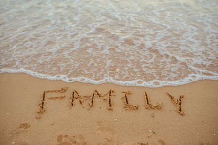 top view FAMILY lettering on the sand of a beach with wave and sunshineの写真素材