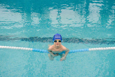 top view of a 7-year boy playing and swimming in the swimming pool smiling and laughingの写真素材