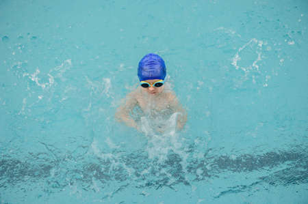 top view of a 7-year boy playing and swimming in the swimming poolの写真素材
