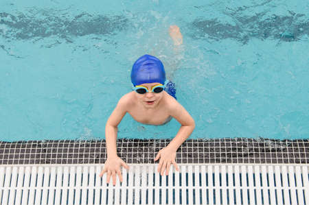 top view of a 7-year boy playing and swimming in the swimming poolの写真素材