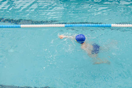 top view of a 7-year boy playing and swimming in the swimming poolの写真素材