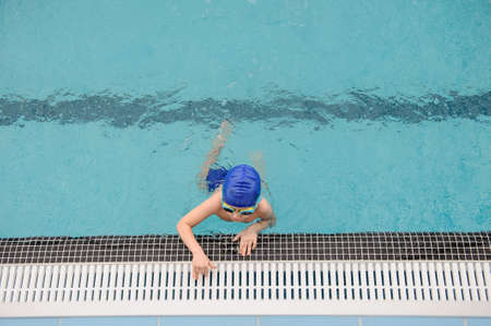 top view of a 7-year boy playing and swimming in the swimming poolの写真素材