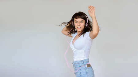 close up photo of a happy brunette with pink headphones in white blouse and denim skirtの写真素材