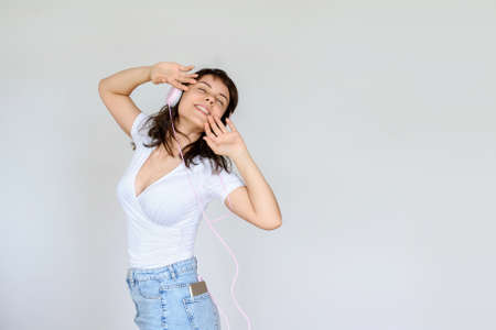 close up photo of a happy brunette with pink headphones in white blouse and denim skirtの写真素材