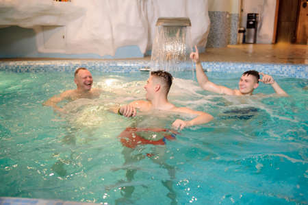 close up photo of 4 men relaxing in swimming pool in a spa centreの写真素材