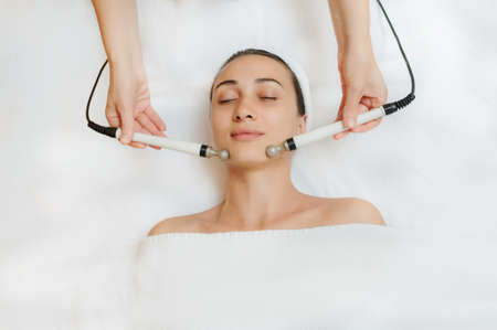 Top view of middle aged woman receiving electrical stimulation facial skin care spa procedure. Micro-current lift face. Beauty spa procedure. Anti aging rejuvenation non surgical treatment in medical center.の写真素材
