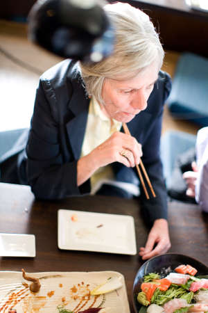 A senior female office worker eating at a Japanese themed restaurantの写真素材
