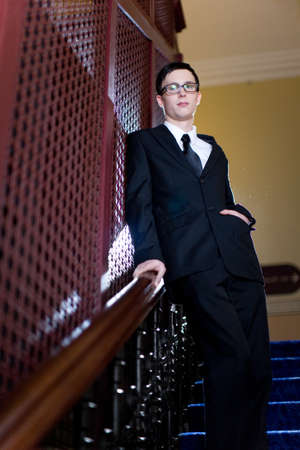 A young well dressed man leans against an elevator cage, left hand in pocket.の写真素材