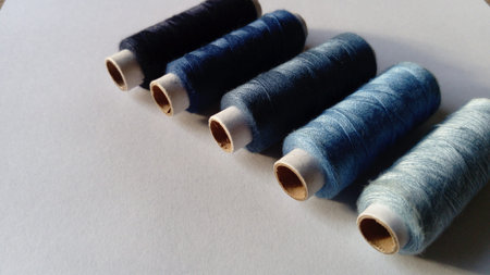 Close-up of threads in different shades of blue. Spools of thread located on a white background in a...