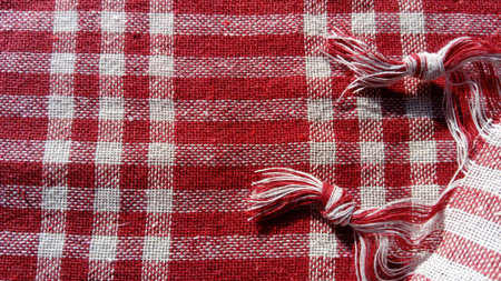 Red and white checked kitchen cloth with two tassels of thread