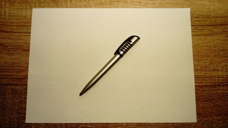 A ballpoint pen lies on a white sheet of paper. Paper lies on a wooden tableの写真素材