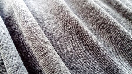 Stretched elastic fabric. Gray material laid in waves. Cloth for sewing covers for chairs, chairs and sofas and for sewing clothes, plush toys, bedspreads and other fabric products.の写真素材