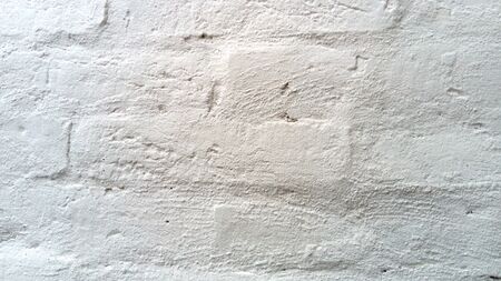 Uneven brick wall painted white. White bricks close-up. The texture of the old brick. The play of light and shadow. Exterior Sample. The appearance of the facade of a brick building or fence.の写真素材