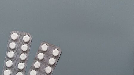 Two plates with white pills, factory-packaged in blisters, on a gray background. Medication in the form of conventional tablets. Copy space.の写真素材